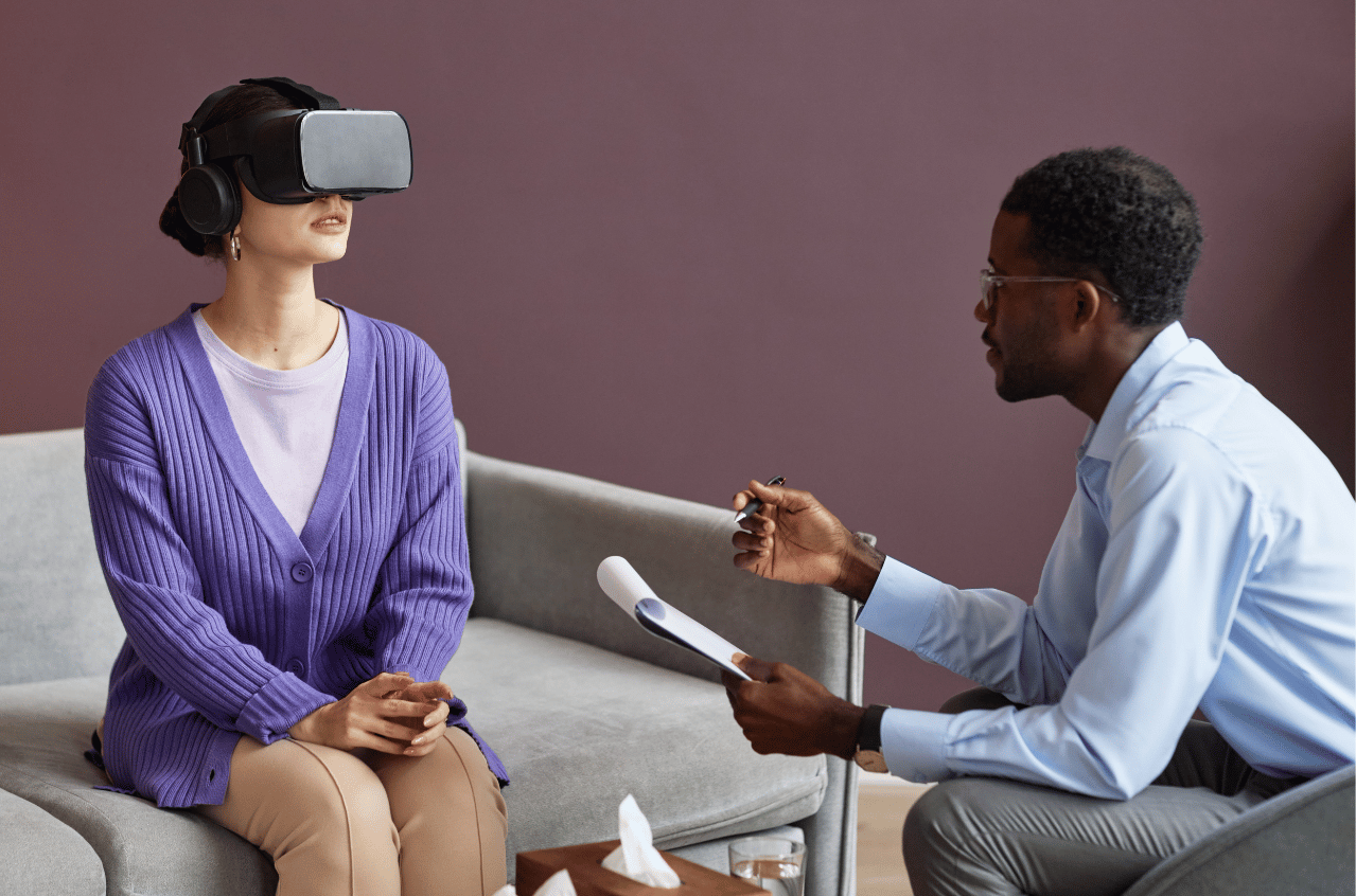Image of a woman wearing a VR headset, speaking with a therapist during exposure therapy