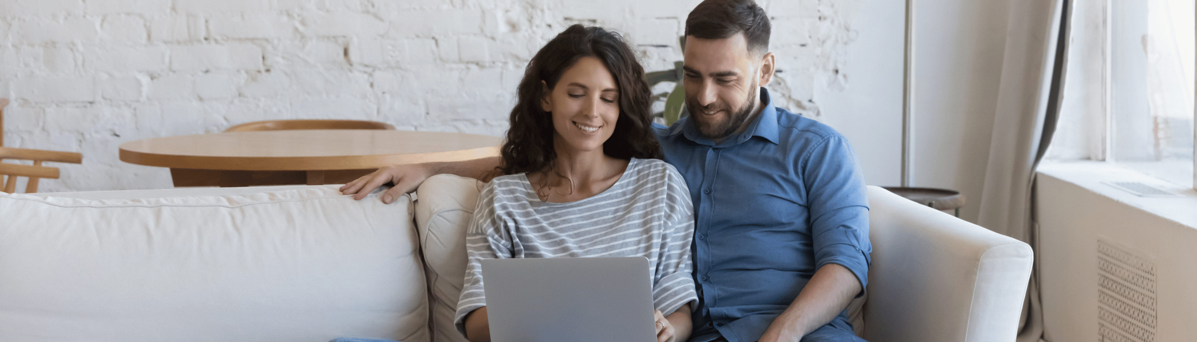 Woman with long dark hair with dark haired partner looking at laptop screen